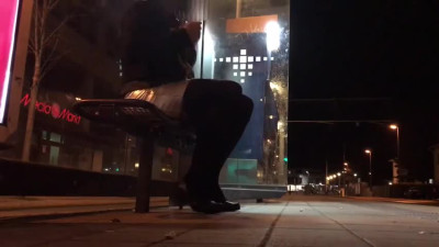 Crossdresser fixed on a bench at a tram station